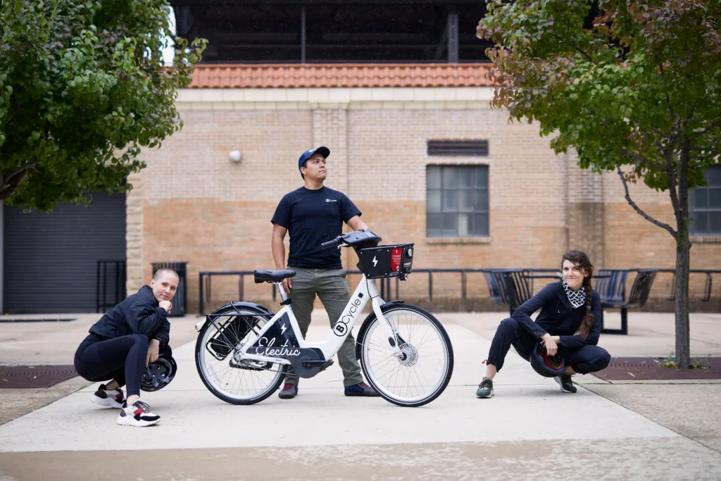 Photo of three people posing around a bike share bicycle