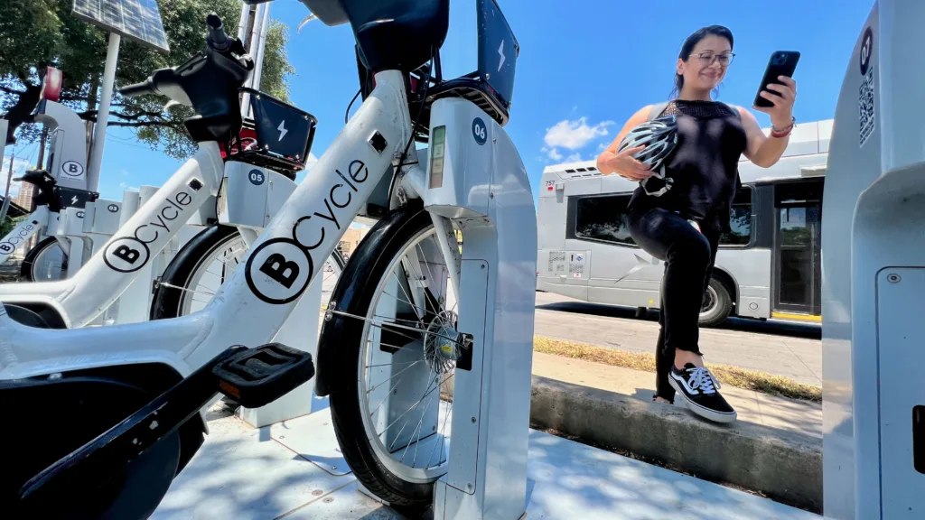 Latina using her smart phone to access the BCycle app so she can check out a bike share.